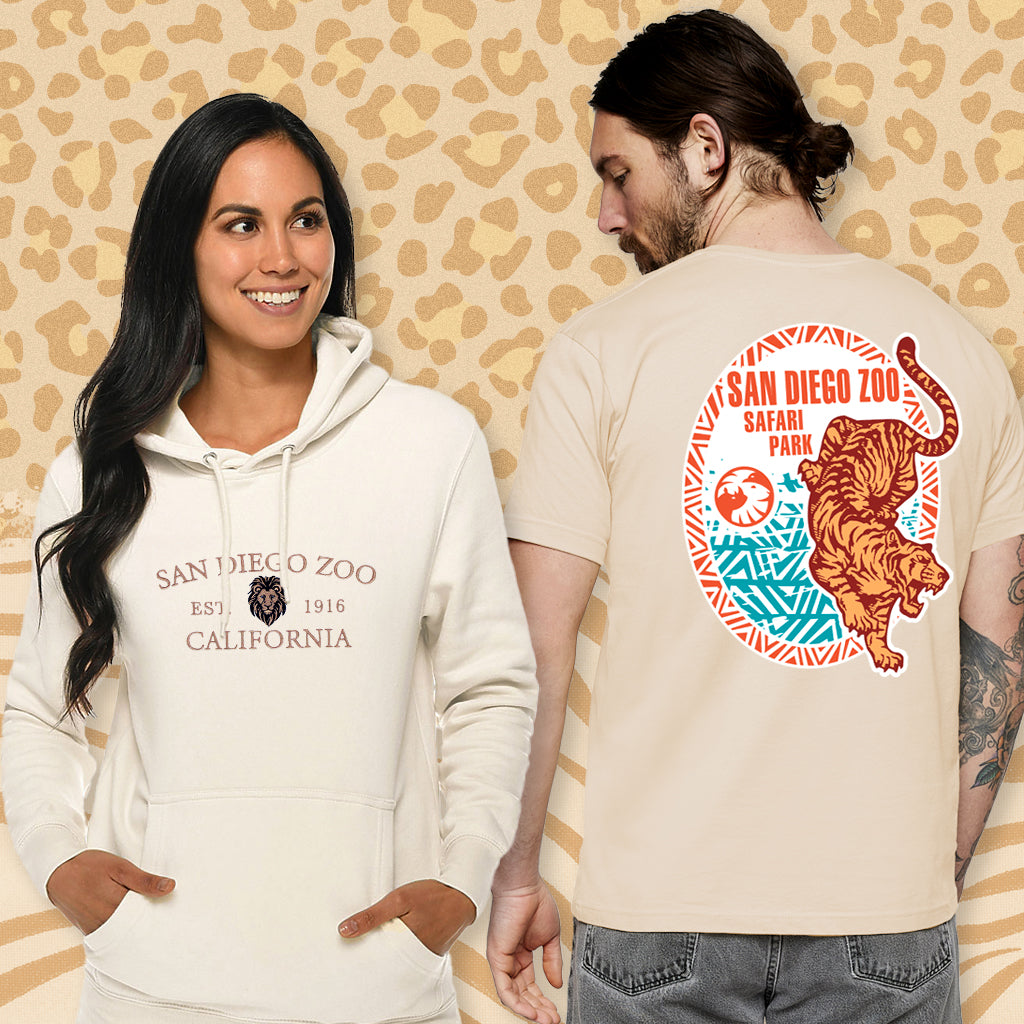 Two people wearing San Diego Zoo big cats-themed clothing against a wildlife-patterned background.