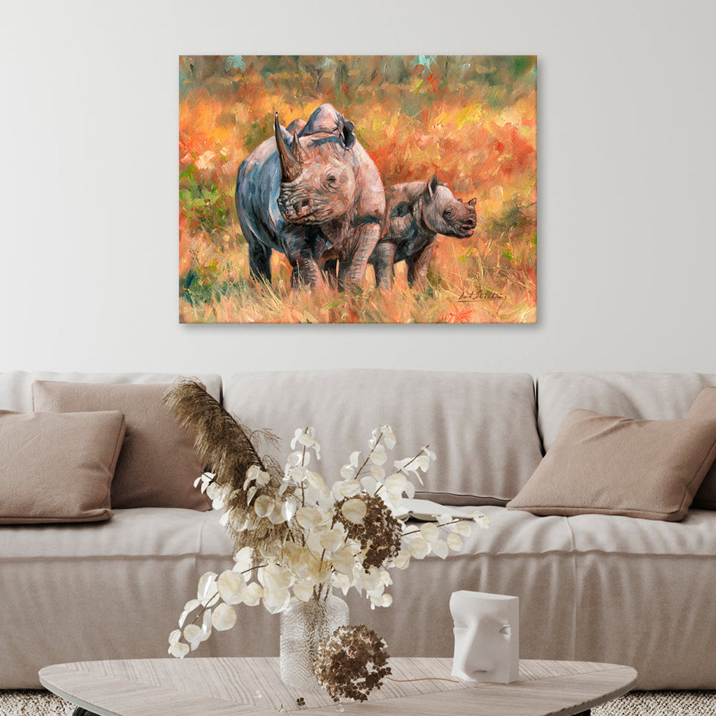 Canvas print of two rhinos in a natural setting above a beige sofa with decorative items.
