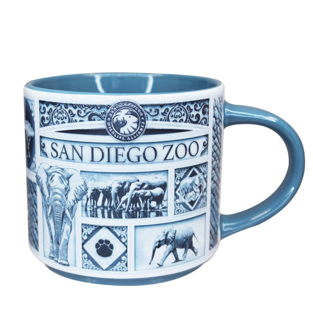A Delft style ceramic San Diego Zoo mug with a blue handle and interior, decorated with blue and white illustrations of elephants and the San Diego Zoo logo.