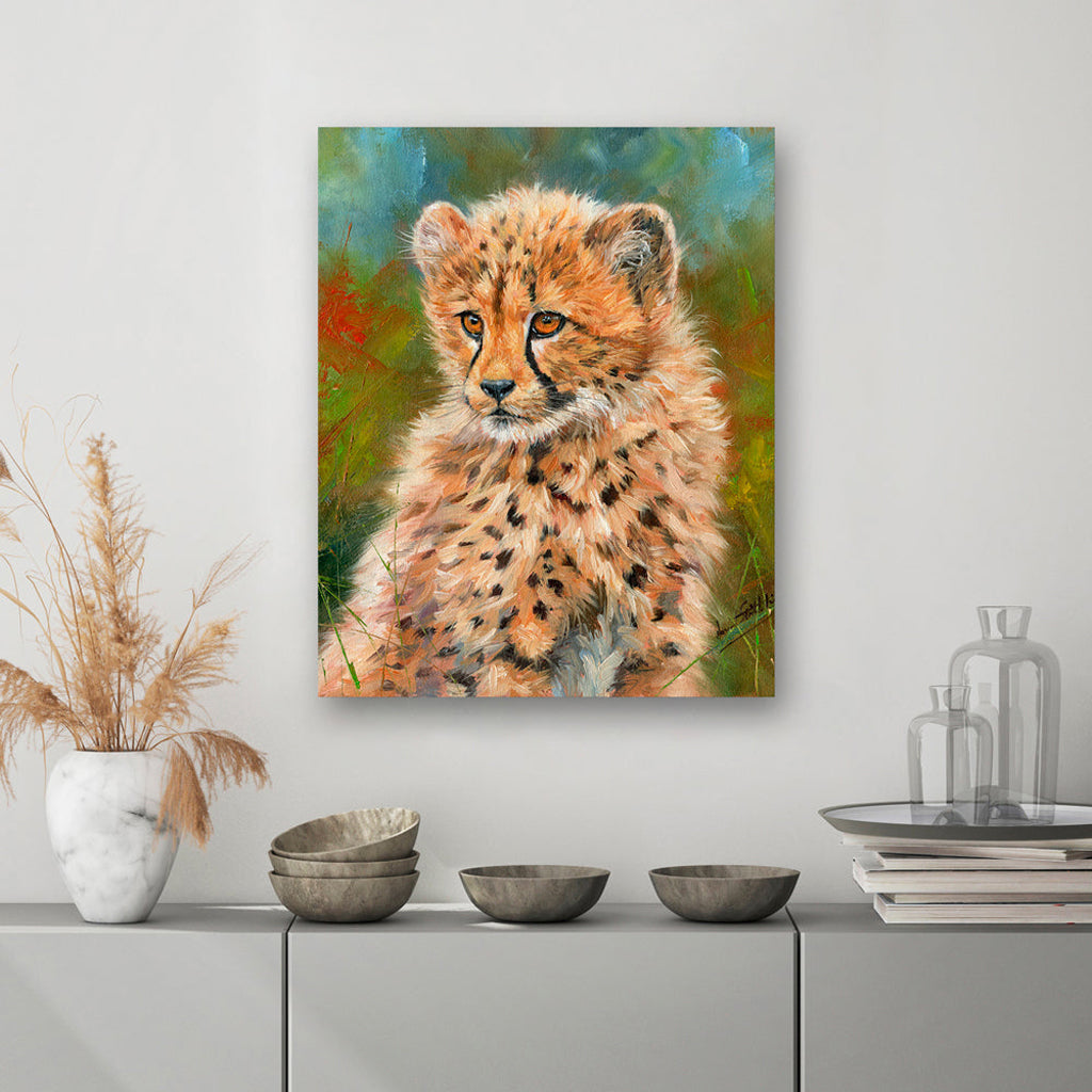 Canvas Print Painting of a cheetah cub on a wall above a cabinet with decorative items.