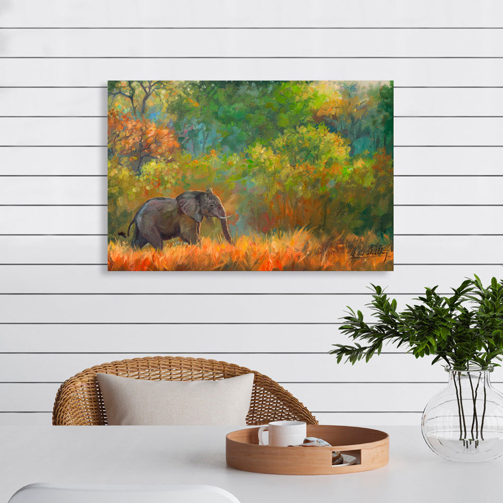 Canvas Print Painting of an elephant in a forest on a wall above a table with a plant and decorative items.