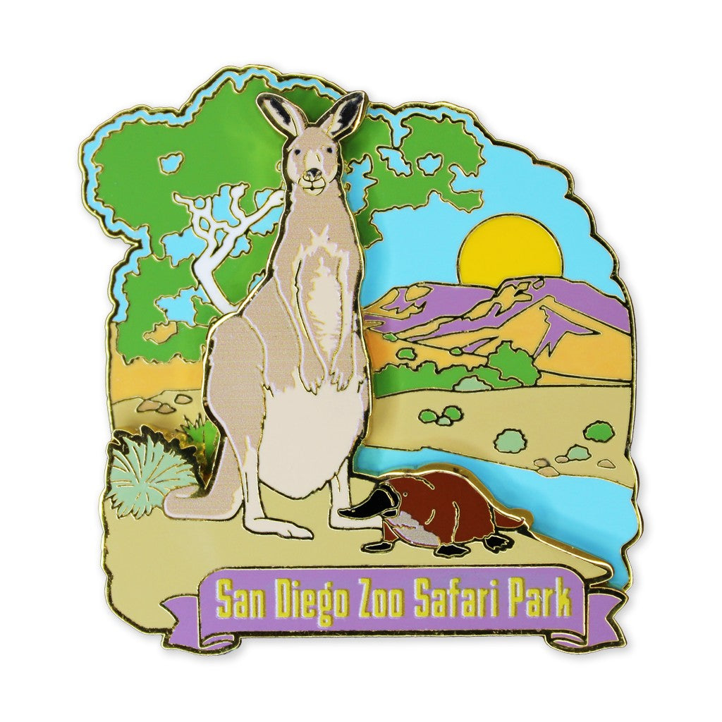A die-cut enamel trading pin featuring a stylized safari scene with a kangaroo, a platypus, trees, mountains, and a sun, with the text 'San Diego Zoo Safari Park' on a purple banner at the bottom.