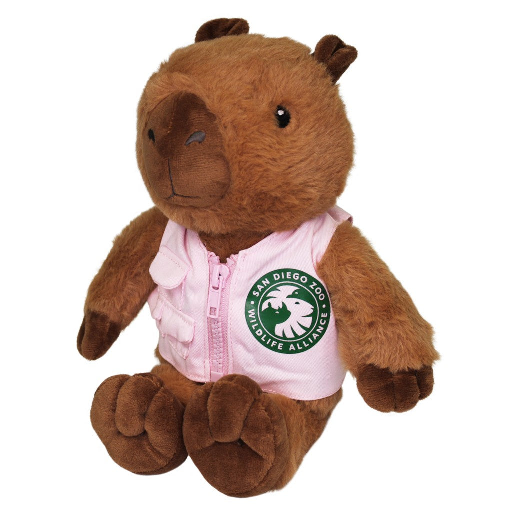 A brown capybara plush toy wearing a light pink zippered vest with a green San Diego Zoo Wildlife Alliance logo on the front. 12-inch plush stuffed animal stuffy