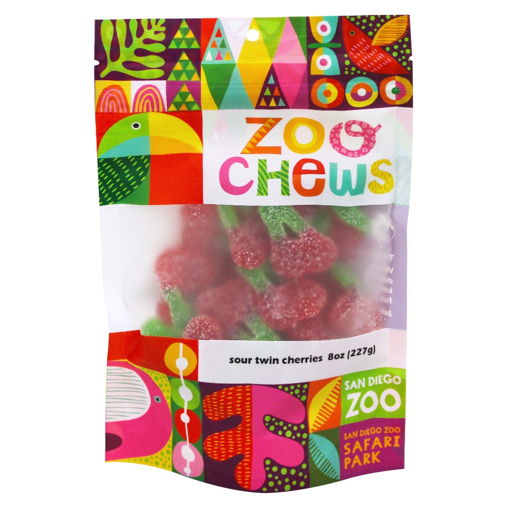 A 8 oz bag of San Diego Zoo Safari Park Sour Twin Cherries gummy candies. The packaging features a vibrant, multicolored geometric pattern with a parrot illustration and a clear window showing the pink-red, sugar-coated cherries inside.